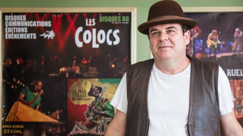 Benoit Gagné, musicien et producteur des Colocs, devant des affiches du groupe mythique.