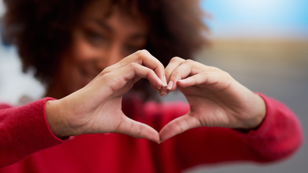 Une femme forme un coeur avec ses mains en signe d'amour.