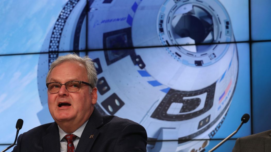 Jim Chilton, vice-président sénior de Boeing, devant une grande affiche de la capsule Starliner.