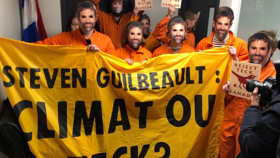 Des militants écologistes habillés en combines oranges occupent les bureaux du ministre du Patrimoine Steven Guilbeault. Ils portent des masques à l'effigie du ministre.