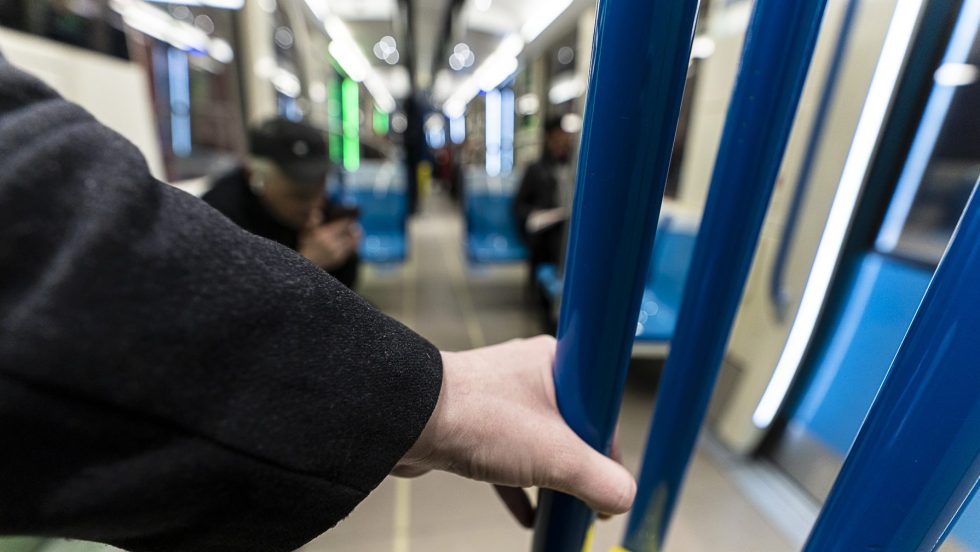 Une personne tient une barre dans un wagon de métro.