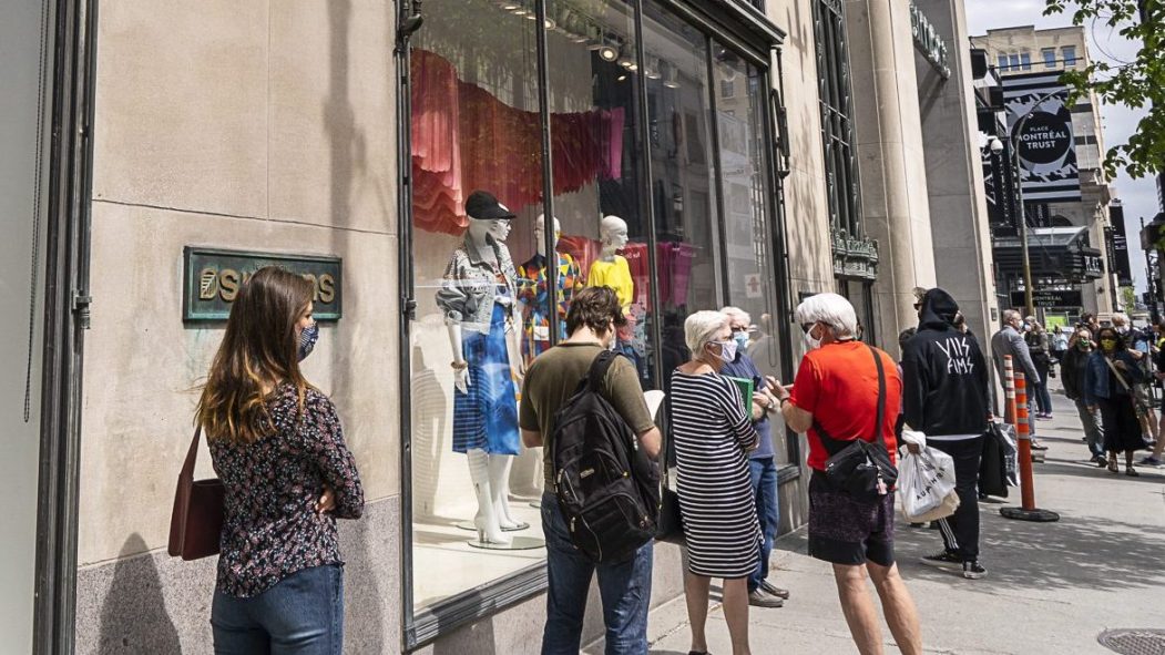 Plusieurs personnes patientent devant le magasin Simons, rue Sainte-Catherine.