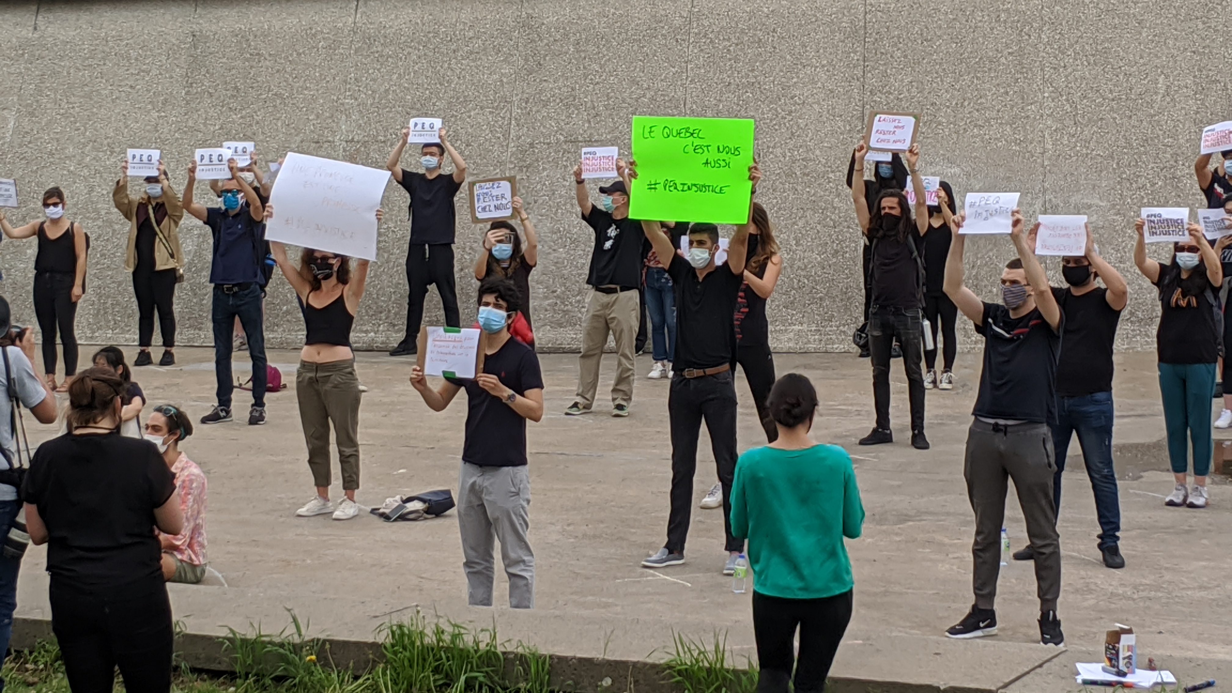 Des manifestants montrent des affiches dénonçant la réforme du PEQ, devant le Stade olympique.