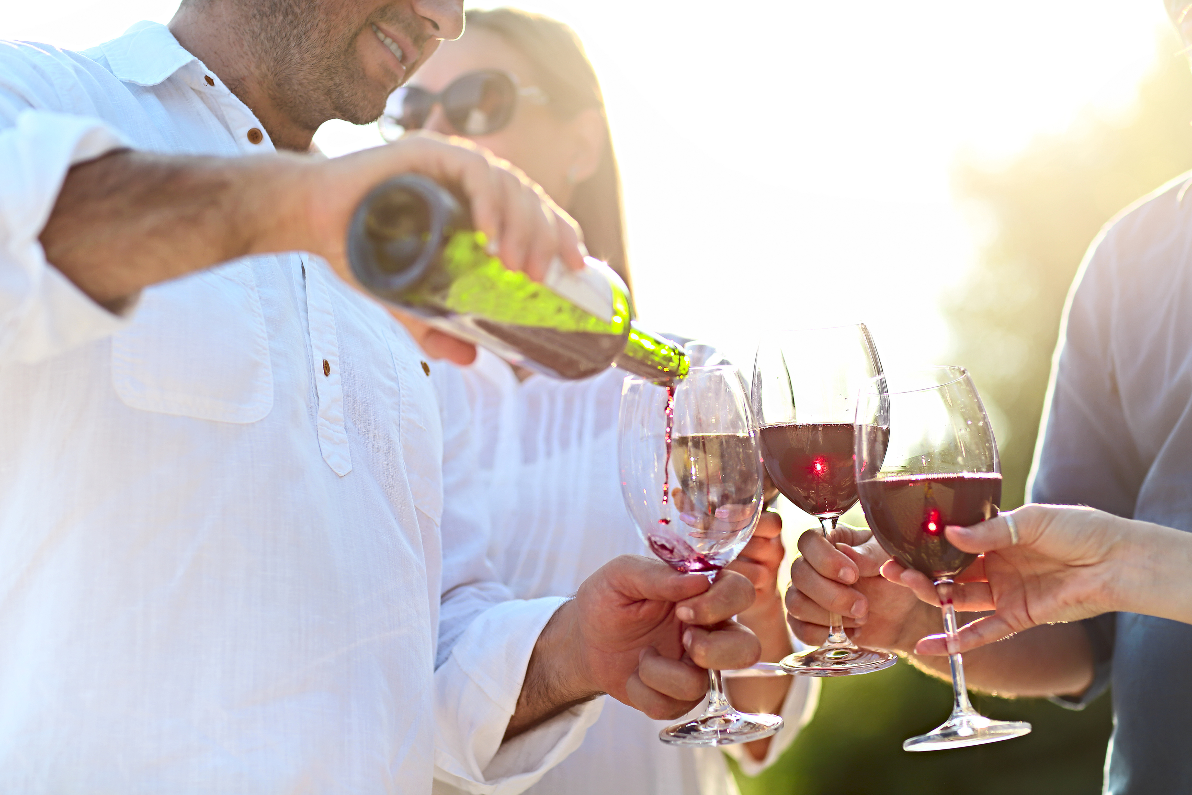 Un homme versant du vin rouge dans des coupes