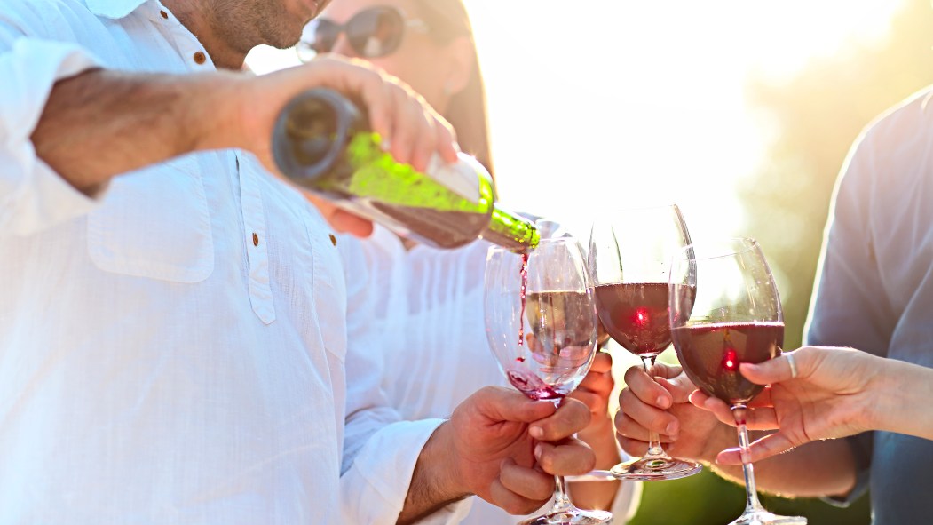 Un homme versant du vin rouge dans des coupes