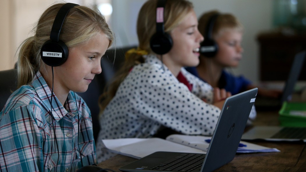 Des enfants utilisent leur appareil électronique pour faire l'école à la maison.