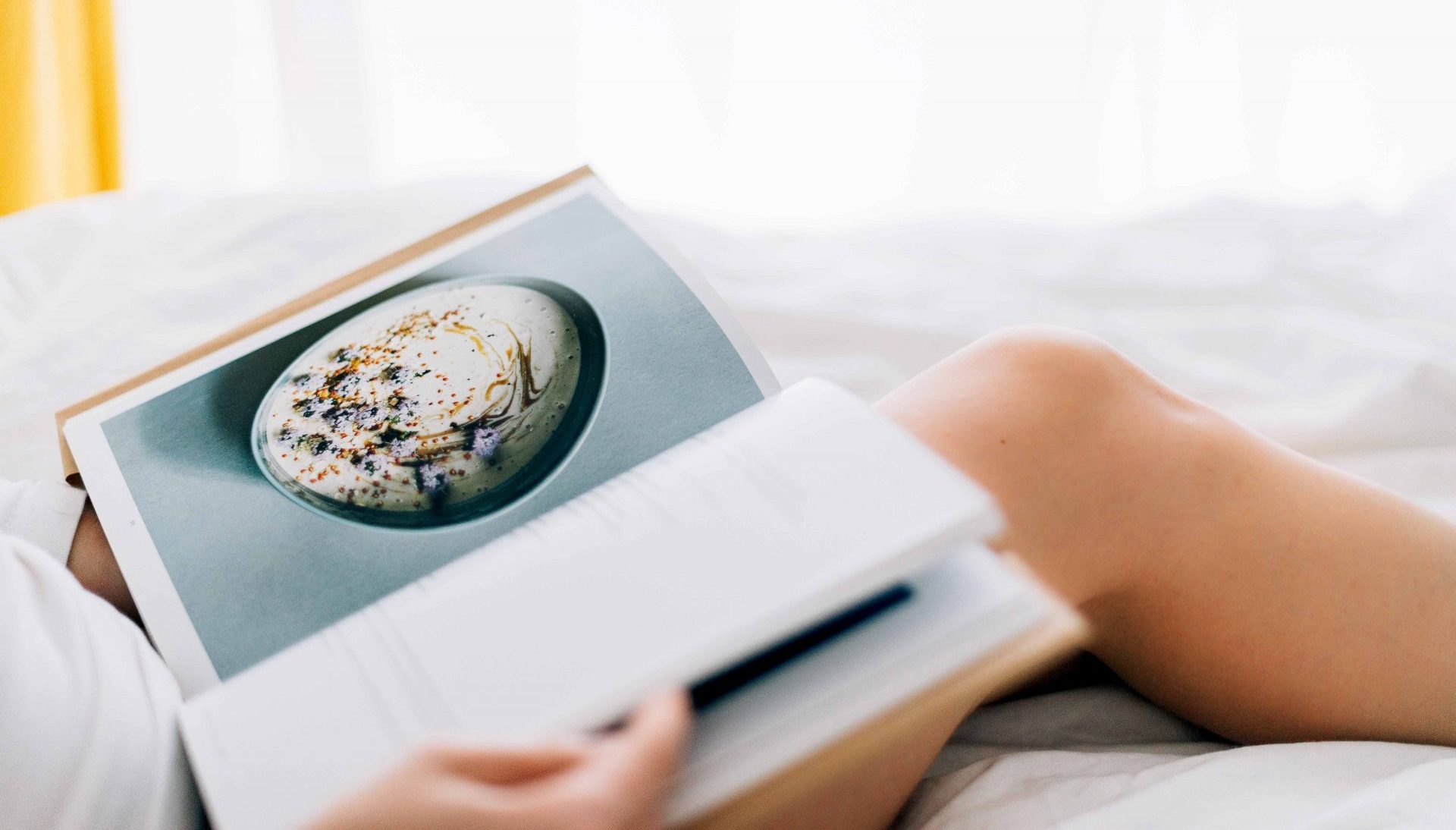 Livre de recettes déposé sur les genoux dénudés d'une jeune femme