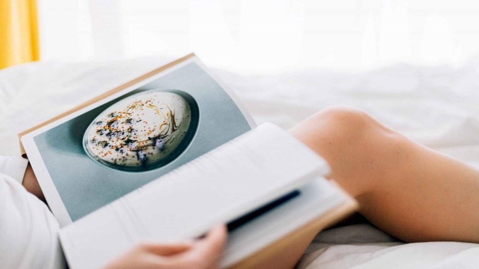 Livre de recettes déposé sur les genoux dénudés d'une jeune femme