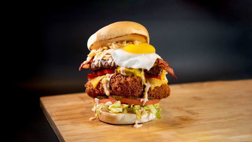 Un burger de poulet amplement garni avec des légumes et un oeuf