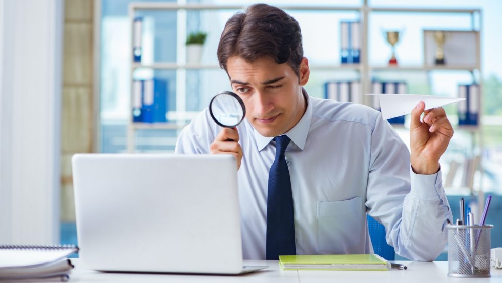 Businessman with magnifying glass and paper plane