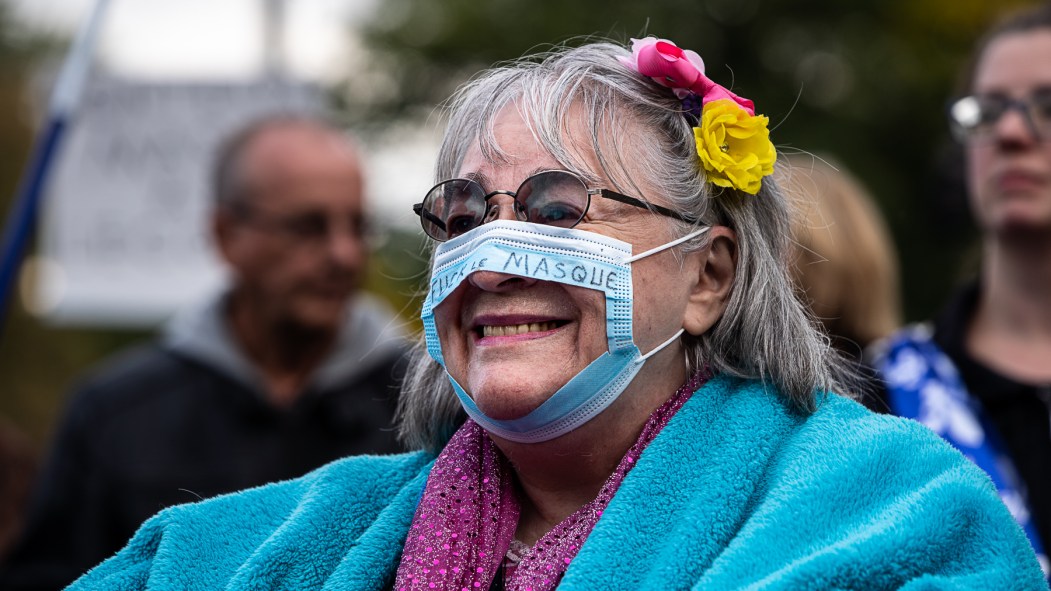 Une femme porte un masque troué lors d'une manifestation anti-masques tenue à Montréal.