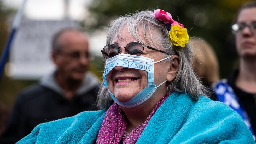 Une femme porte un masque troué lors d'une manifestation anti-masques tenue à Montréal.