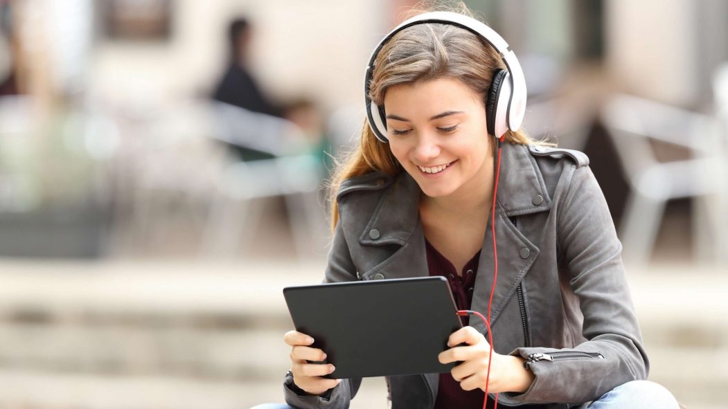 Jeune fille avec des écouteurs regarde sa tablette électronique