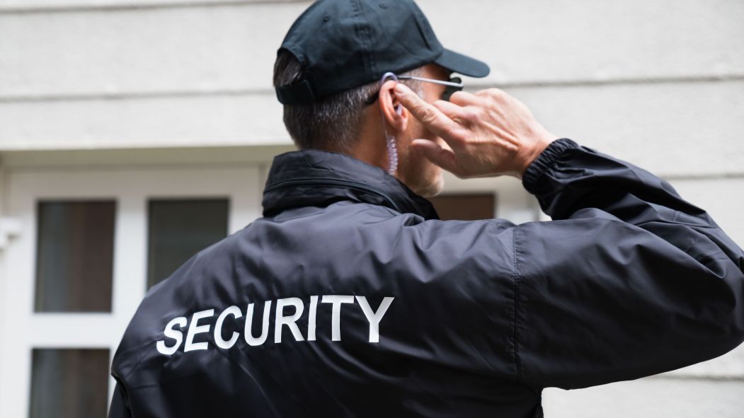 Un agent de sécurité à l'écoute devant une maison, vu de dos. L'Accueil Bonneau a remplacé 11 intervenants en itinérance par des agents de la firme Garda.