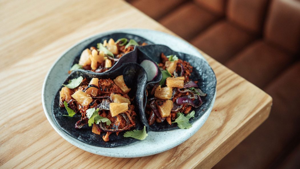 Une assiette contenant trois tacos végétalien posée sur une table