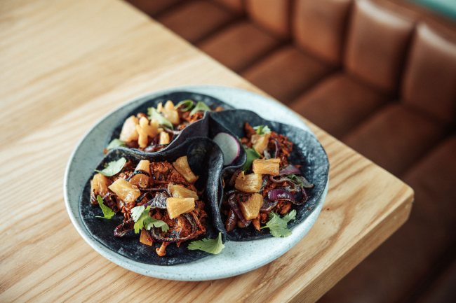 Une assiette contenant trois tacos végétalien posée sur une table