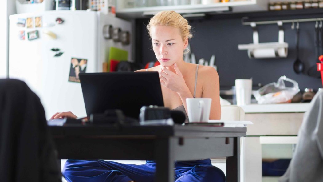 Pigiste Femme dans ses vêtements d'accueil occasionnel de travail remotly de sa table à manger le matin. Accueil cuisine dans l'arrière-plan.