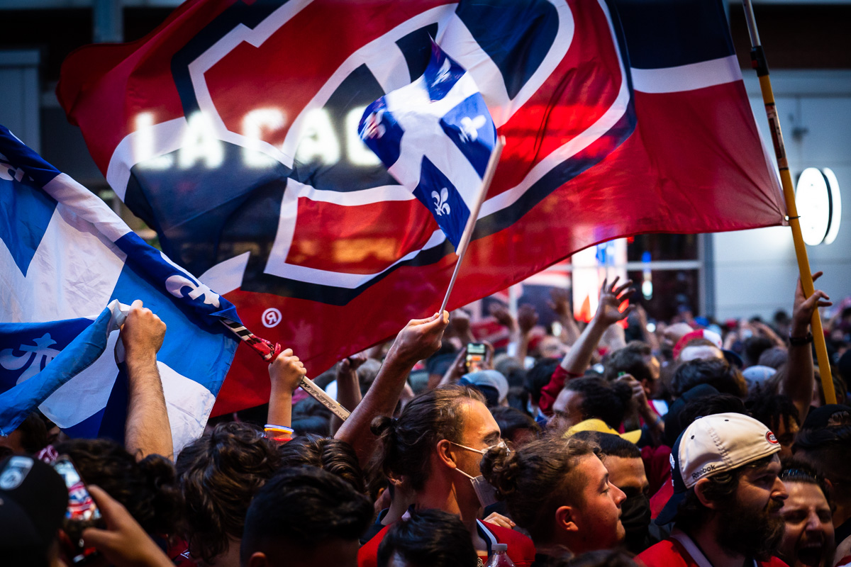 Un drapeau des Canadiens de Montréal flotte au-dessus d'une foule de partisans réunis devant le restaurant La Cage près du Centre Bell.