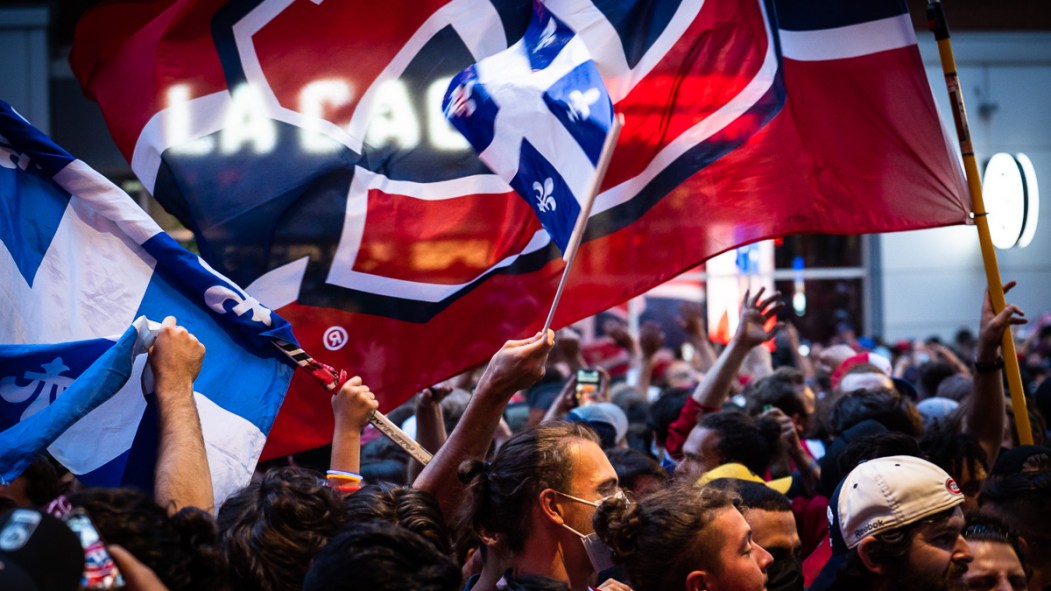 Un drapeau des Canadiens de Montréal flotte au-dessus d'une foule de partisans réunis devant le restaurant La Cage près du Centre Bell.