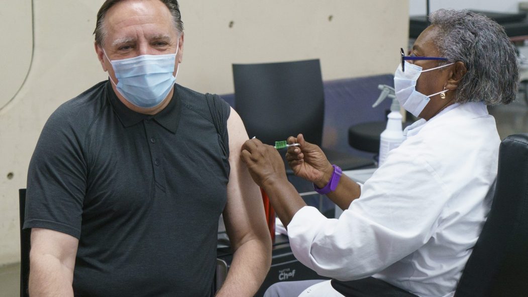 François Legault reçoit sa deuxième dose de vaccin de la part d'une infirmière.