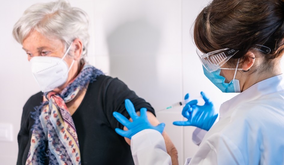 Une infirmière administre une dose de vaccin à une femme âgée.
