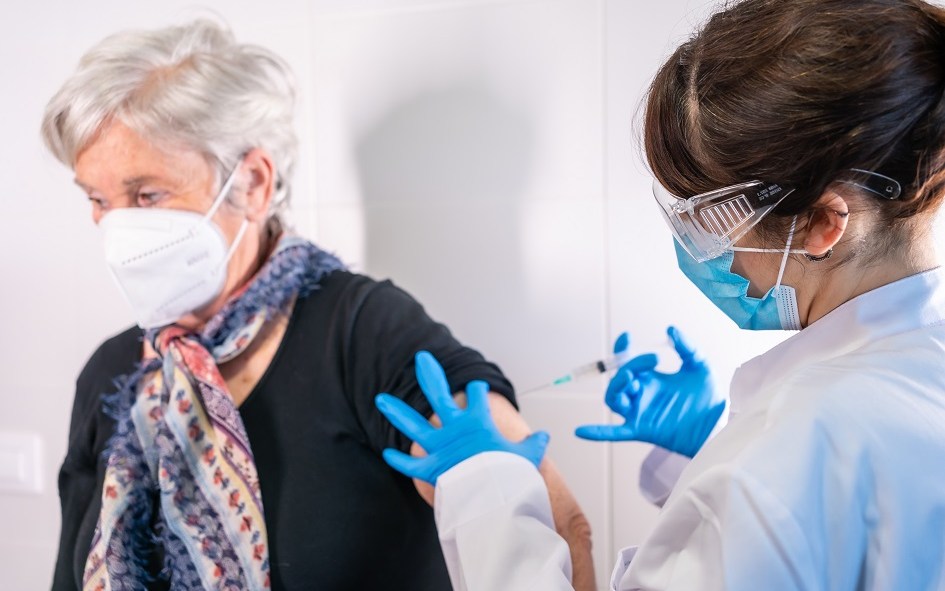 Une infirmière administre une dose de vaccin à une femme âgée.