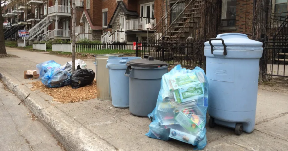 Des sacs et bacs de déchets et de matières résiduelles le long d’un trottoir.