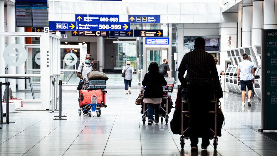 Des voyageurs à l'étage des départs à l'aéroport de Montréal.