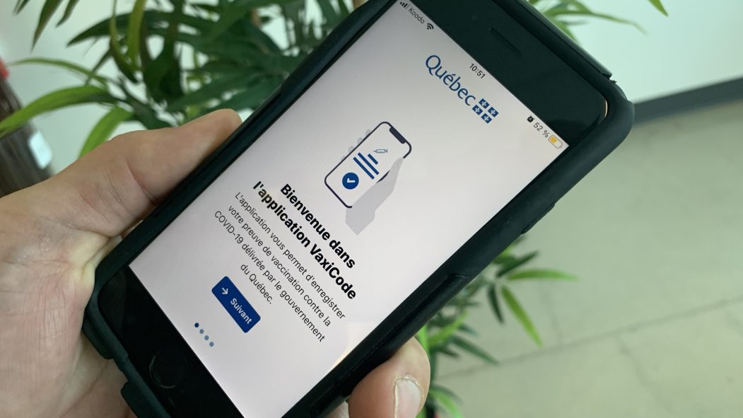 Une main tient un téléphone intelligent. L'application VaxiCode, la plus téléchargée de l'AppStore, est affichée