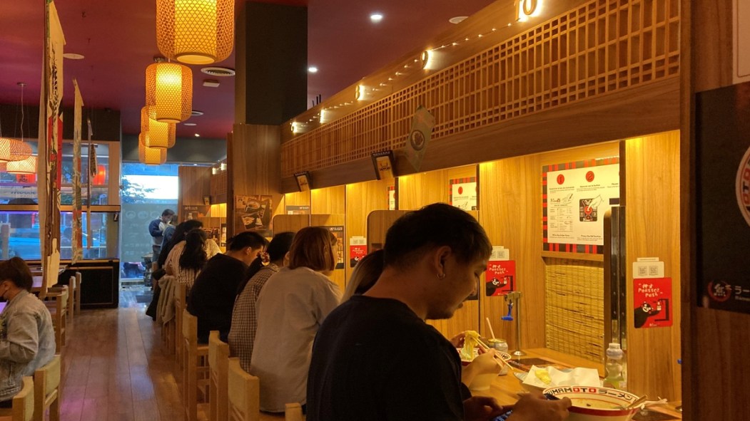 Des clients assis à un comptoir du restaurant japonais Kumamoto Ramen.