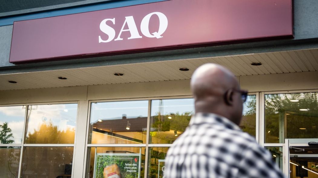 Un homme vu de dos entre dans une succursale de la SAQ, alors qu'une entente de principe est survenue avec le syndicat