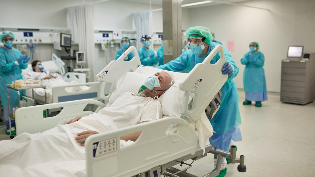 Une personne âgée sur un lit d'hôpital dans une aile d'hospitalisations pour la covid-19.