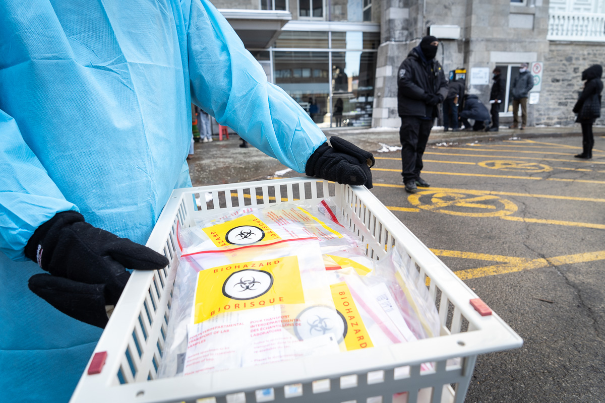 Des employés de la santé distribuent des tests rapides pour la COVID-19 pour faire diminuer les files d'attente au centre de dépistage de l'Hôtel-Dieu.