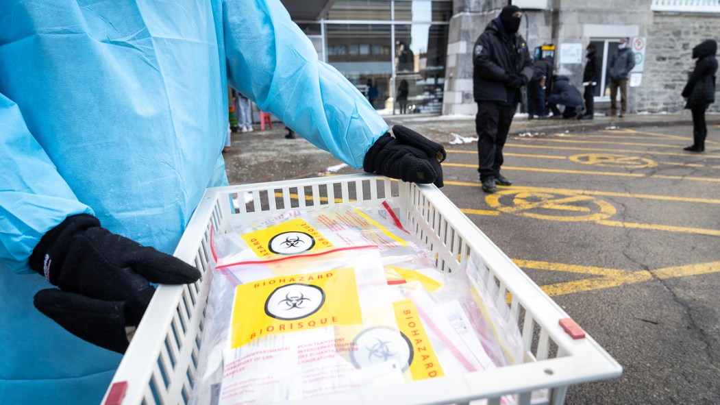 Des employés de la santé distribuent des tests rapides pour la COVID-19 pour faire diminuer les files d'attente au centre de dépistage de l'Hôtel-Dieu.