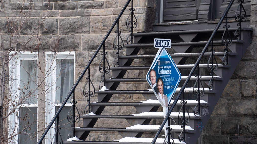 Une affiche à vendre installée devant les escaliers d'un condo de Montréal