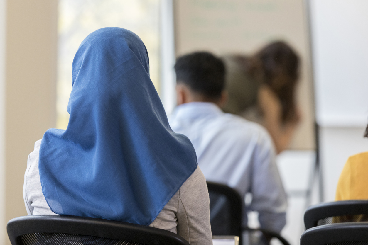 femme de dos, en classe à l'école, qui porte le voile, hidjab