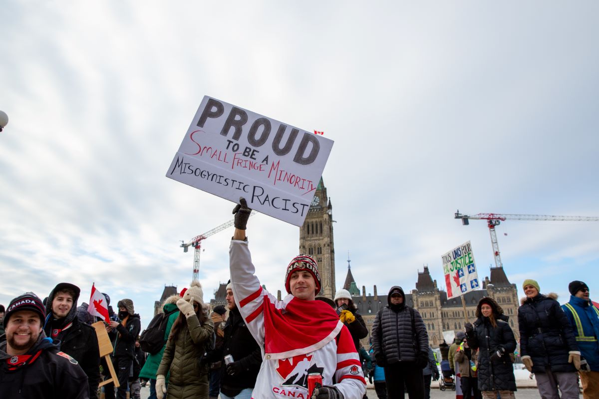 Un manifestant tient une pancarte raciste et misogyne lors de la manifestation de camionneurs à Ottawa