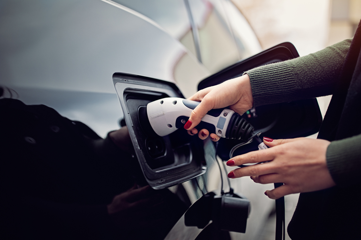 Une personne portant du vernis à ongle recharge une voiture électrique.