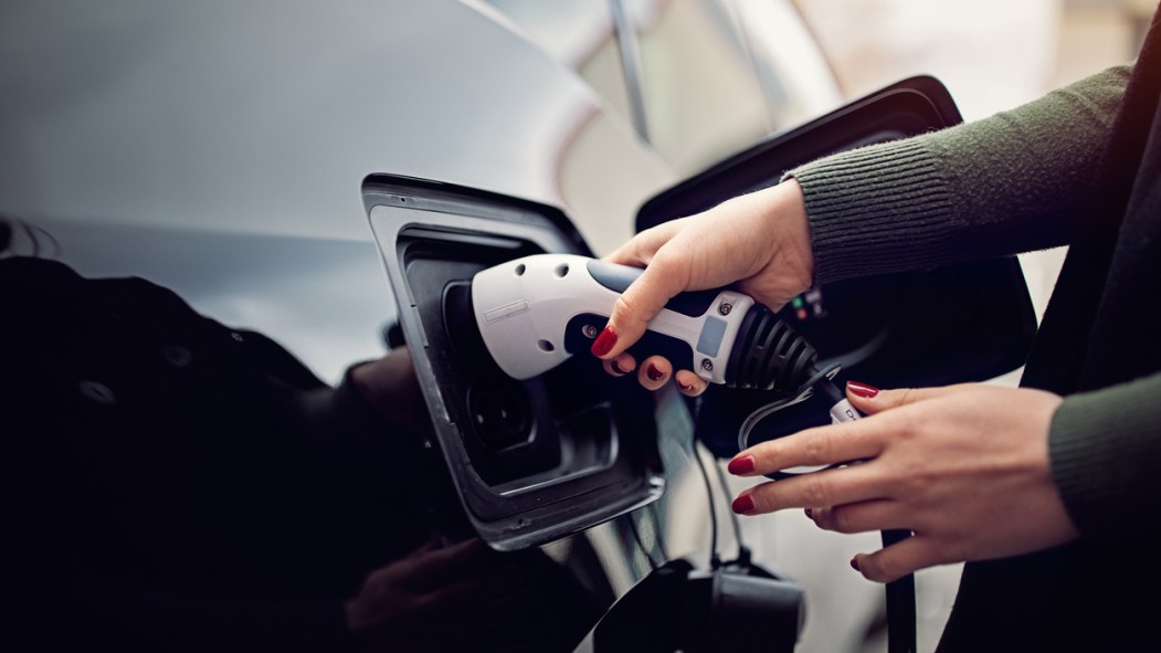 Une personne portant du vernis à ongle recharge une voiture électrique.