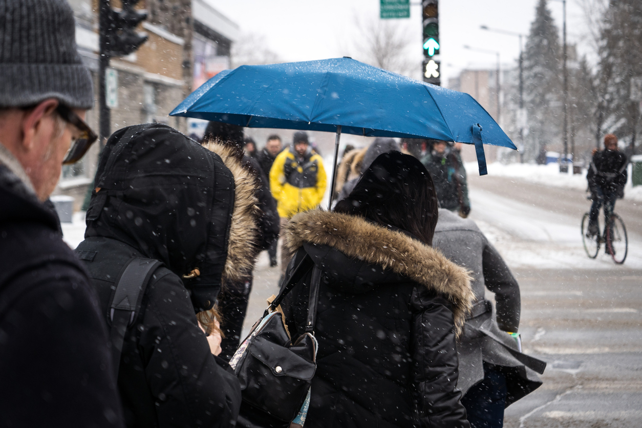 pluie et neige pour la région de Montréal. Des gens traversent une rue avec des parapluies