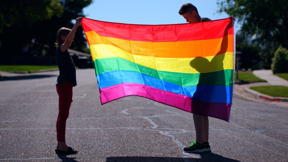 Des personnes tenant le drapeau LGBTQ+.