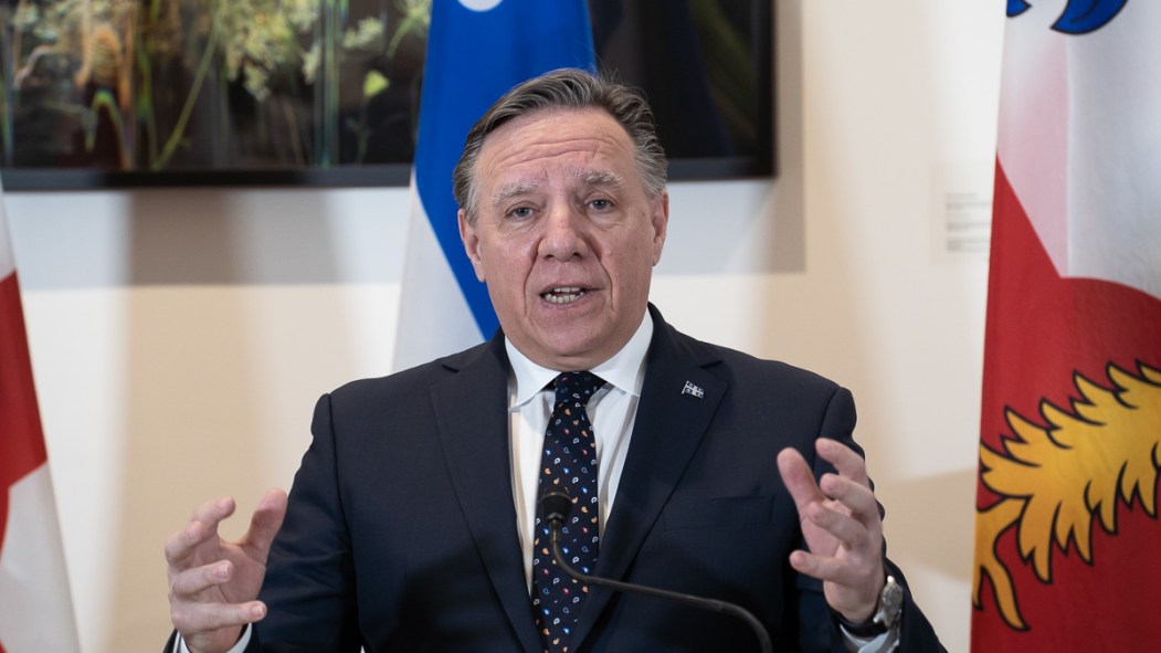 François Legault devant un drapeau du Québec à l'hôtel de ville de Montréal.