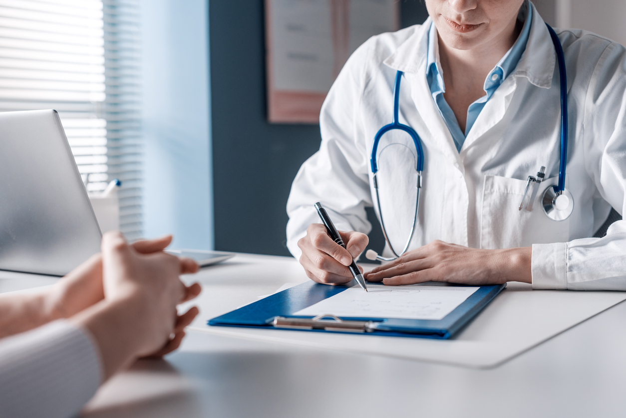 un médecin assis à un bureau fait un prescription pour une patiente