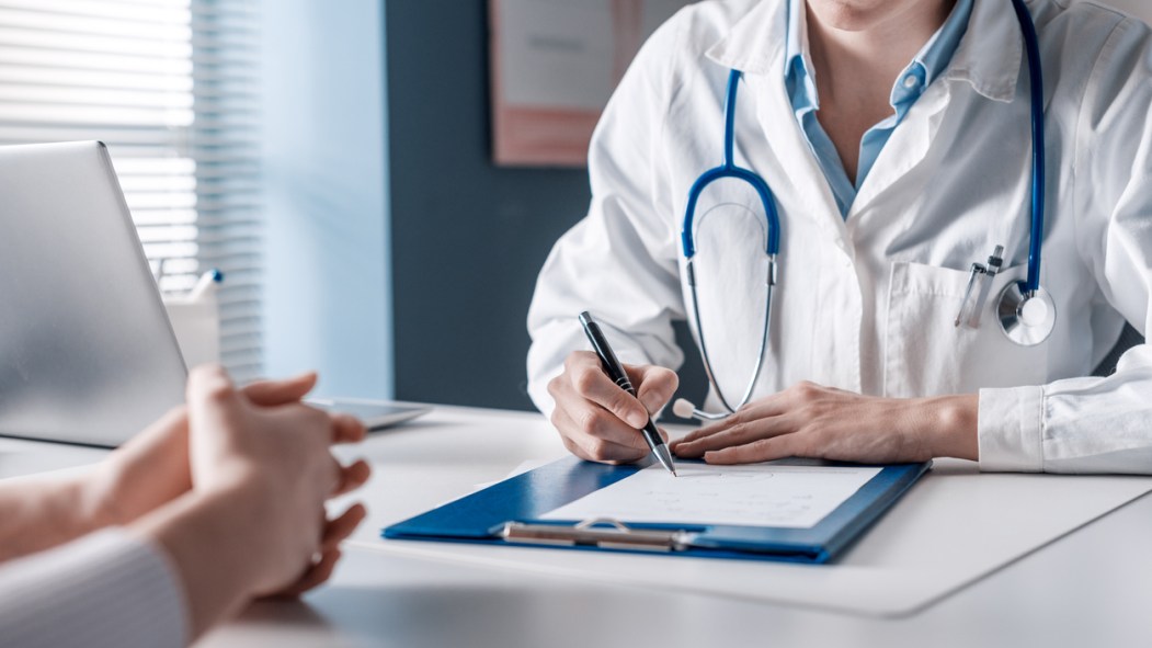 un médecin assis à un bureau fait un prescription pour une patiente