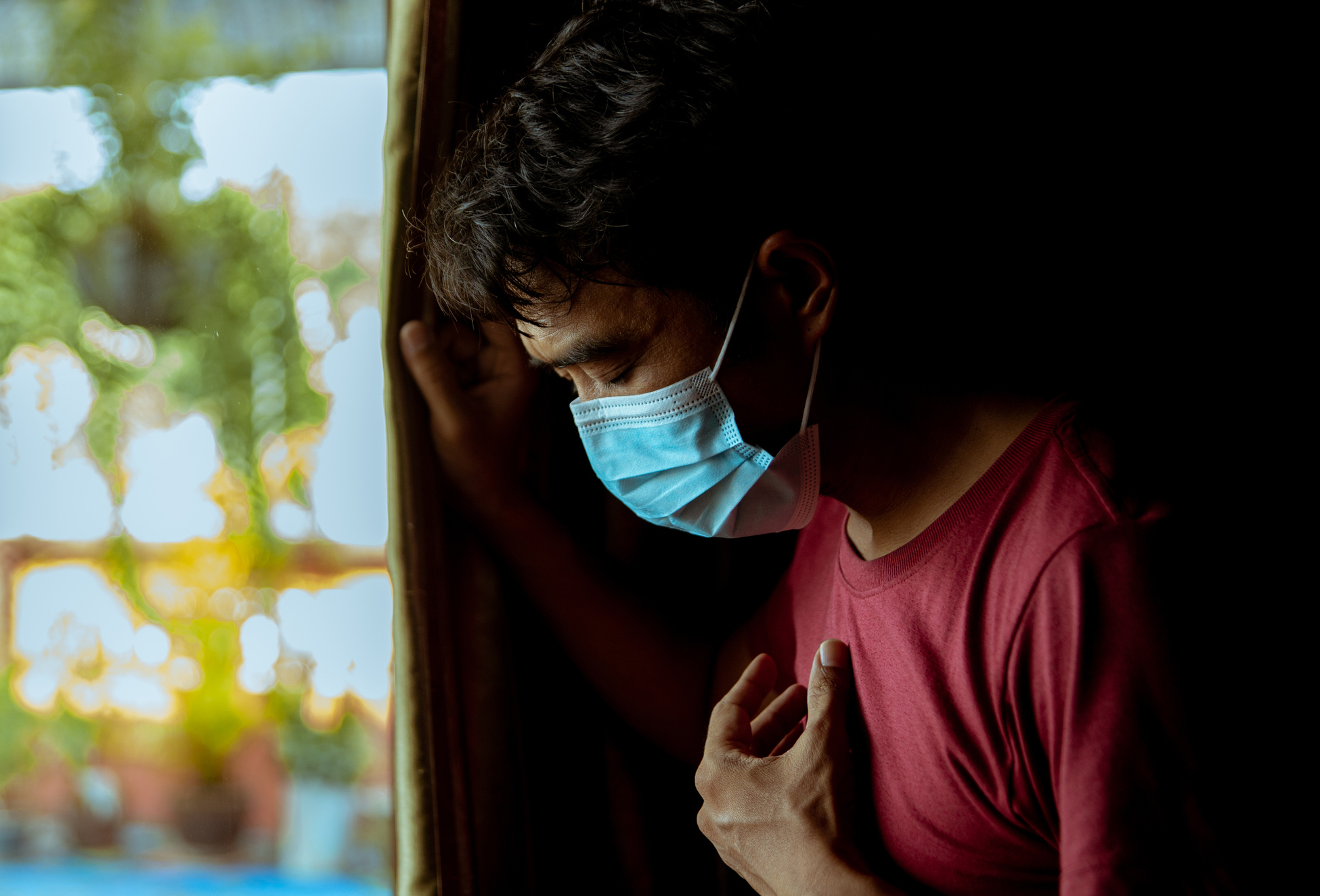 Un homme porte sa main à sa poitrine, montrant des difficultés respiratoires liées à la COVID longue.