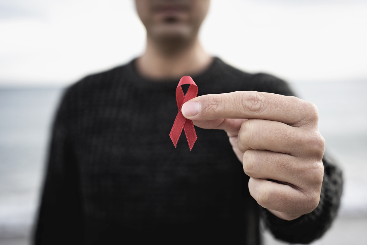 Un homme tient un ruban rouge, symbole de la lutte au sida.