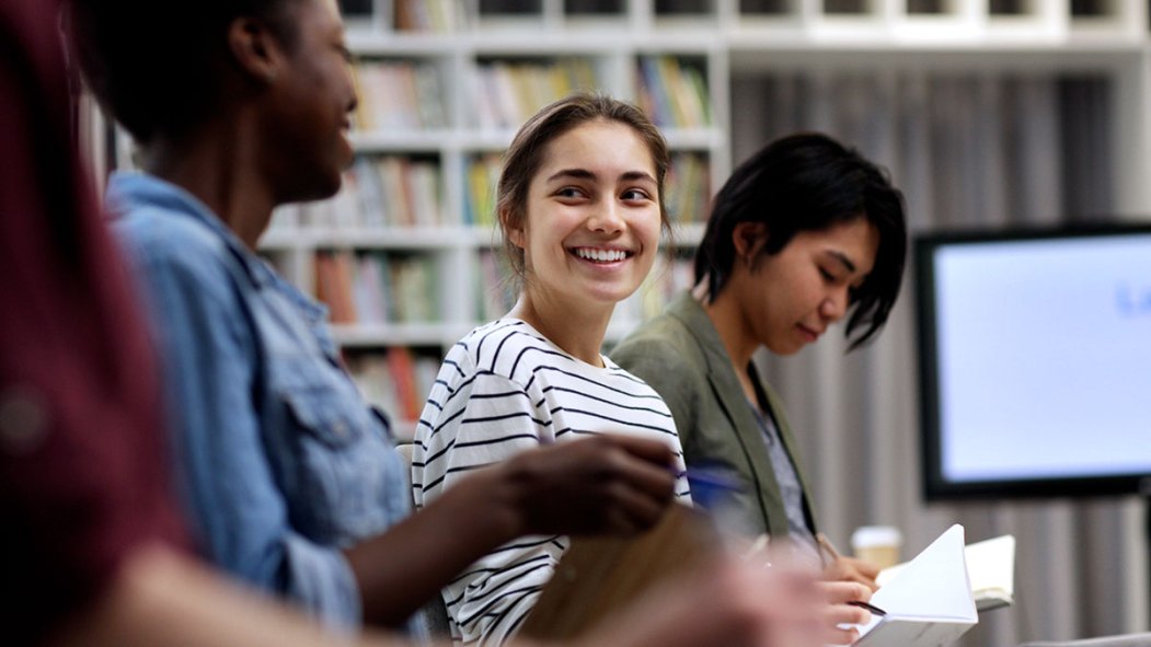 Une jeune femme sourit entourée d'autres jeunes issus de la diversité.