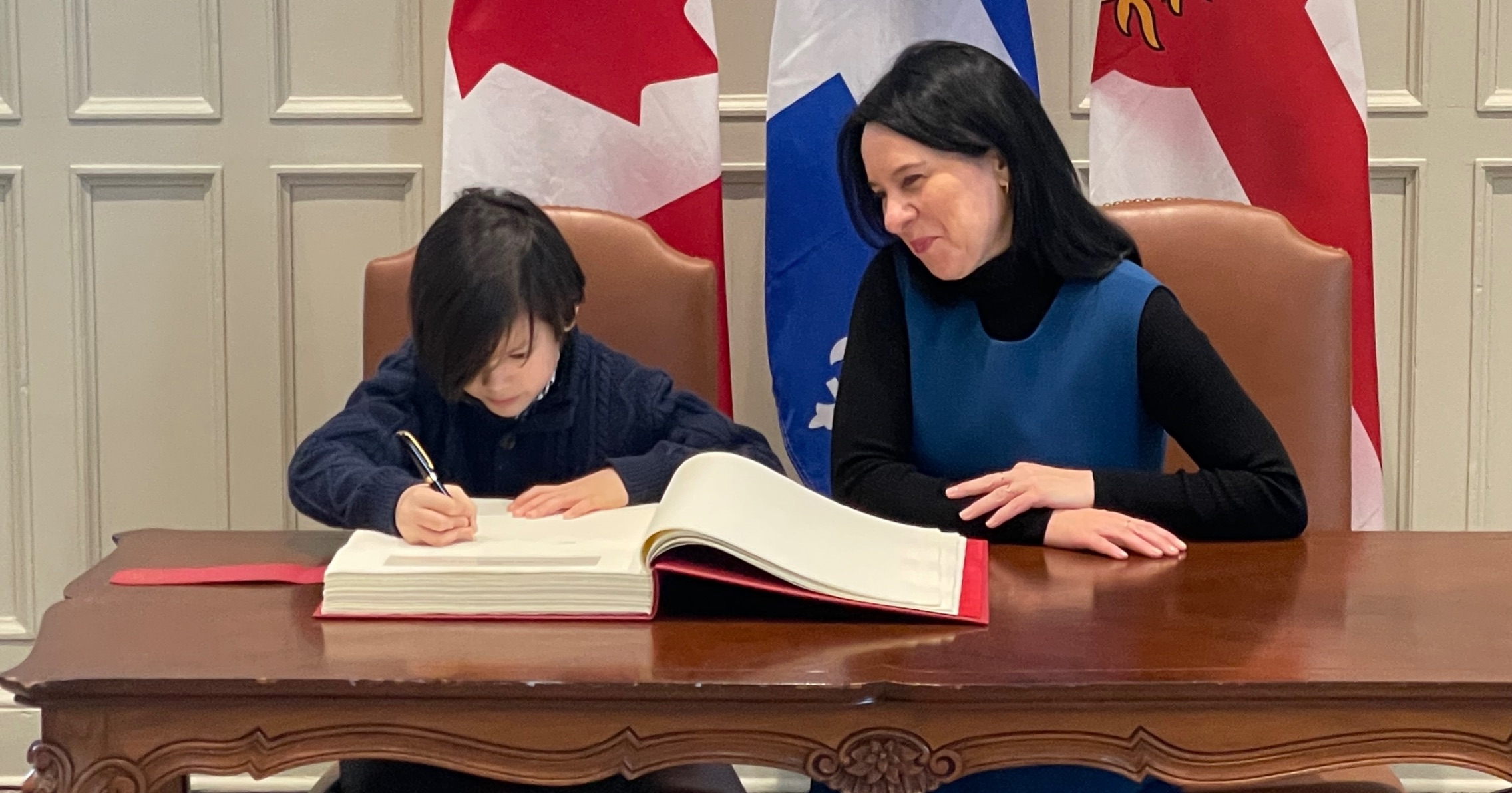 Le jeune Robert signe le livre d'or de la Ville de Montréal aux côtés de la mairesse Plante.