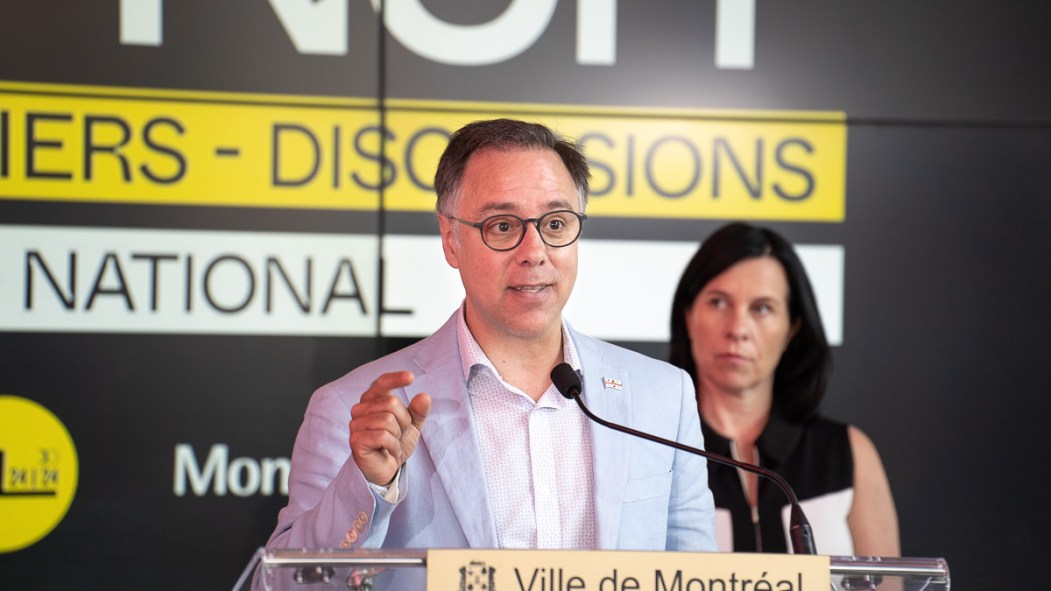 Luc Rabouin devant un lutrin, flanqué de Valérie Plante.